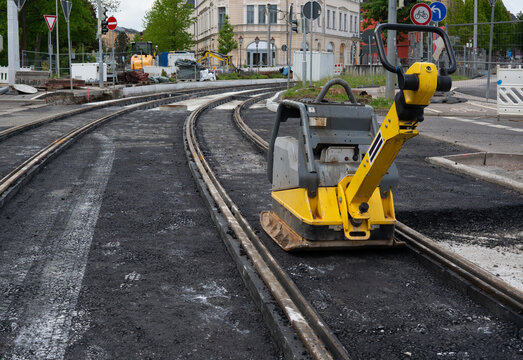 Rehabilitation of the city's rail network using asphalt and a vibratory plate.