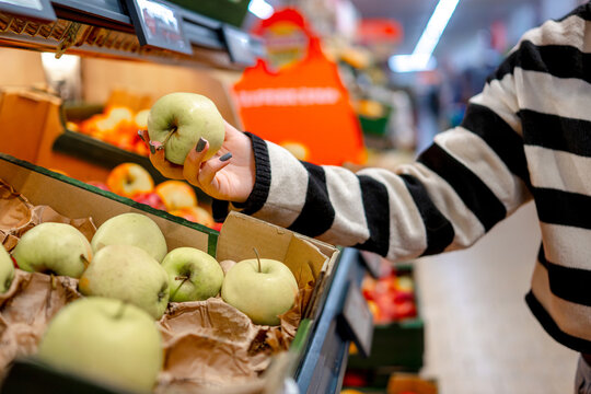 Woman In Supermarket Choosing Apples