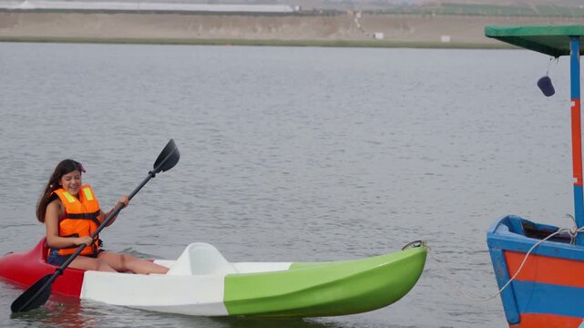 Young woman in life jacket kayaking on a calm lake
