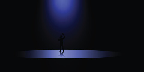 A lone figure stands under a spotlight in a dark room with a raised hand © Khaleda