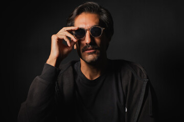 Obraz premium Man in sunglasses strikes a cool pose against a dark backdrop