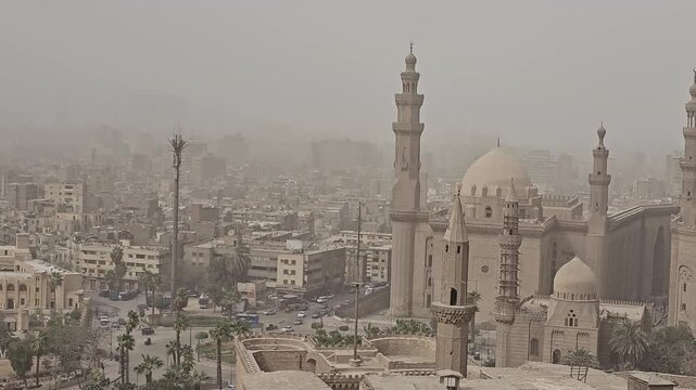 Bird's eye view of ancient Islamic architecture in Cairo, Egypt, featuring the iconic Sultan Hassan Mosque complex with minarets, domes and medieval stone walls.
