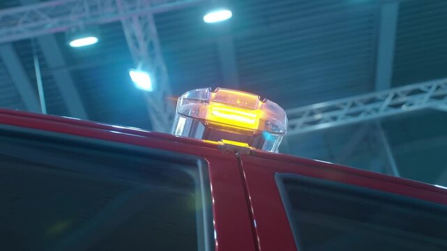 A flashing yellow light flashes on the red roof of an SUV at an exhibition. Shot in motion