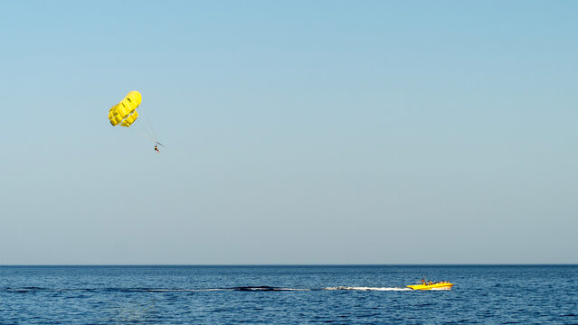 Yellow parachute soars over calm ocean waters