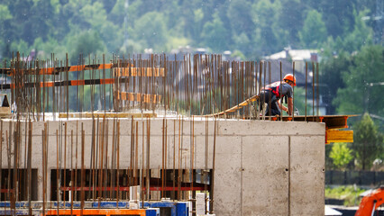 Worker in orange helmet stands on concrete foundation © I