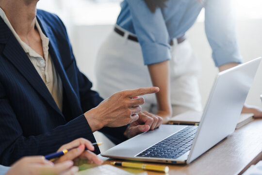 Business professionals discussing work using a laptop in an office meeting, focusing on strategy, teamwork, and project development