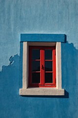 Obraz premium Portrait of red window on blue wall background 