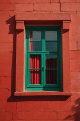 Fototapeta premium Portrait of green window on red wall background 