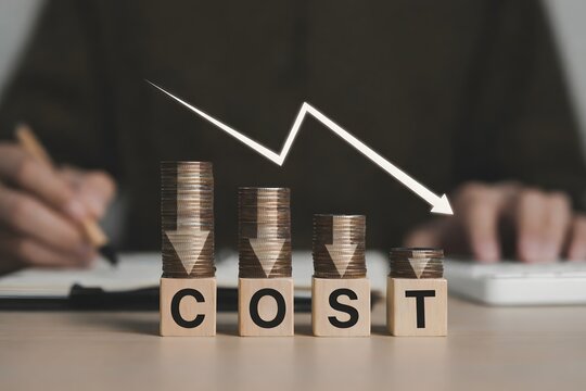 Cost reduction concept. Cost wording on decreasing coins stacking with the down arrow. Businessman working on company cost saving. Cost Management, Economy recession, low budget, Effective business,