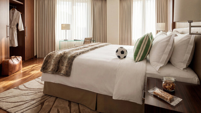 Luxury hotel bedroom with soccer ball, suitcase and snacks, sports travel accommodation concept for football fans, team lodging, tournament tourism and comfortable hospitality stay