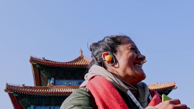 Smiling tourist listening to audioguide in Forbidden City, Beijing