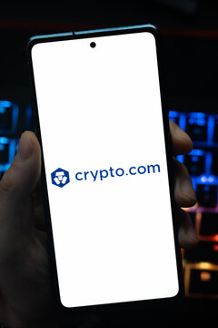 Punta Arenas, Chile &ndash; May 18, 2026: A person holding a smartphone that displays the Crypto.com company logo on its screen, with a blurry multi-colored backlit keyboard in the background