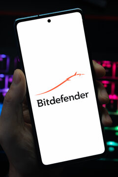 Punta Arenas, Chile &ndash; May 18, 2026: A person holding a smartphone that displays the Bitdefender antivirus software logo on its screen, with a blurry multi-colored backlit keyboard in the background