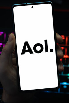 Punta Arenas, Chile &ndash; May 18, 2026: A person holding a smartphone that displays the AOL media and web portal logo on its screen, with a blurry multi-colored backlit keyboard in the background