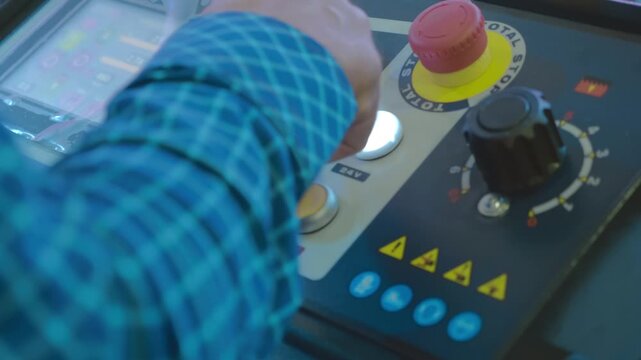 A man's hand presses various buttons and turns knobs on the control panel of a modern machine and controls data input on a monitor. Closeup