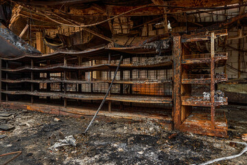 Fototapeta premium Empty warped metal shelves in a burned commercial building.