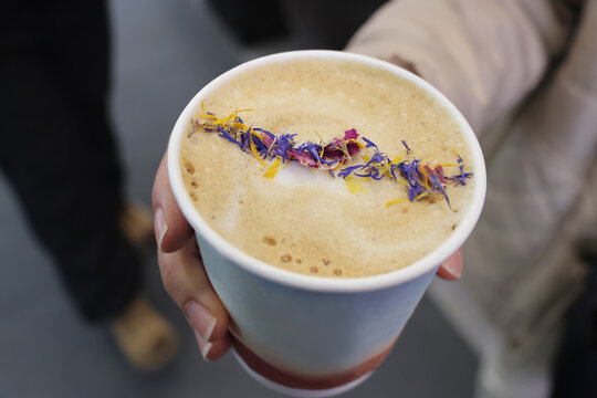 Hand holding a cup of latte with petals on top  at Emei Shan, Sichuan Province of China