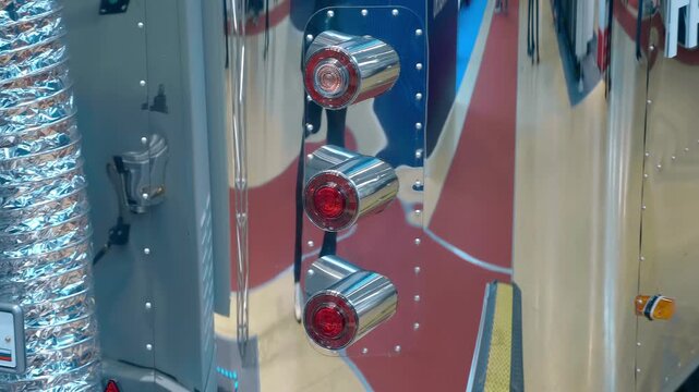 Red taillights on a chrome van, in which, like in a mirror, the surroundings are reflected. Closeup. Shot in motion