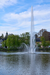 Fototapeta premium Altenburg / Germany: View from the eastern shore over the Big Pond with the high towering fountain to the historic St. Nicholas steeple in the back