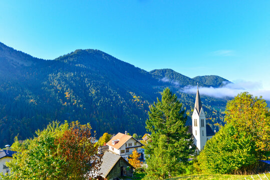 Blick auf die Pfarrkirche hl. Nikolaus in Laterns-Thal vor herbstlich bewaldeter Bergkulisse, Vorarlberg