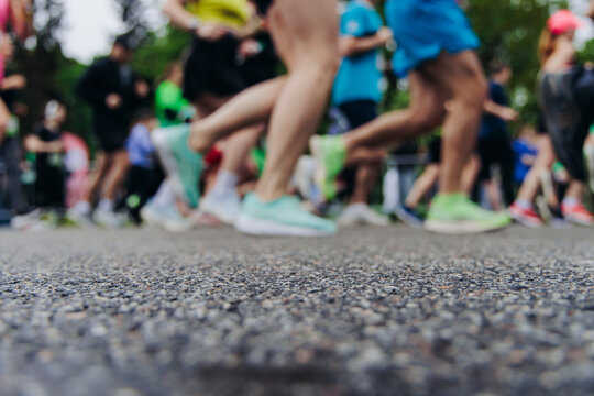 Marathon runners crowd, sportsmen participants start running the half-marathon in the city streets, crowd of sportswomen joggers in motion, group of athletes outdoor training competition in summer day