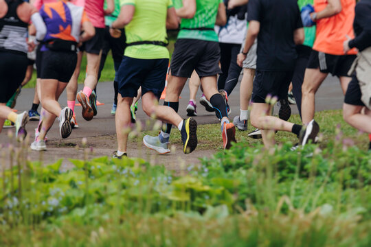 Marathon runners crowd, sportsmen participants start running the half-marathon in the city streets, crowd of sportswomen joggers in motion, group of athletes outdoor training competition in summer day