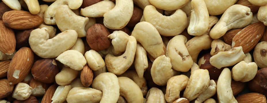 Almond and cashew nuts in big pile on table close up. Large amount of brown nuts
