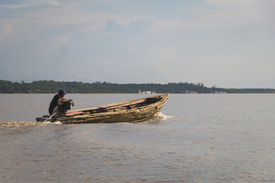 Hombre no identificable conduciendo su canoa sobre las aguas del Rio Amazonas, Iquitos Per&uacute;, amazonia