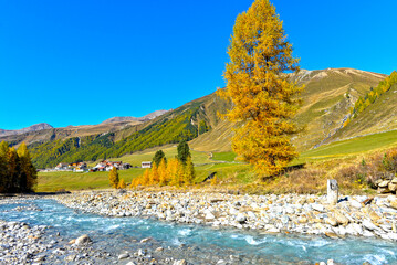 Blick über den steinigen Karlinbach auf den Weiler Melag im herbstlichen Langtauferer Tal, Südtirol © Ilhan Balta