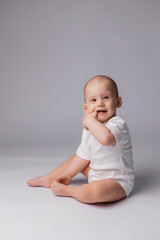 Fototapeta premium baby in a white bodysuit is sitting on a white background in the studio