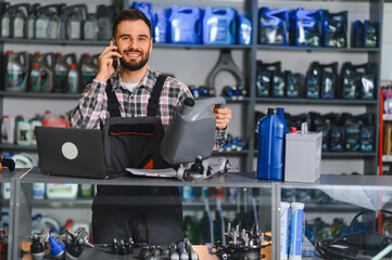 Mechanic talking on phone holding oil in auto parts store