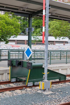 Green Railway Buffer Stop at Urban Train Platform With Blue Priority Sign and End-of-Line Tracks