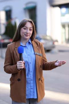 Professional journalist with microphone working on city street