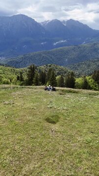 Hikers resting on Baiu Mountains meadow with Bucegi view spring