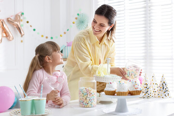 Birthday celebration. Mother and daughter preparing candy bar for festive party at home © New Africa