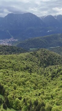 Baiu Mountains forested slopes aerial toward Bucegi peaks in Romania