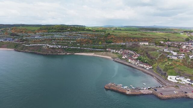 Aerial cinematic drone forward flyover shot of Pettycur Bay sandy beach, holiday caravan park and scenic coastline, Fife, Scotland