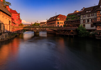 Naklejka premium Half timbered houses by canals of Petite France in Strasbourg, France at sunset