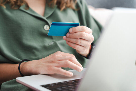 A person uses a credit card and laptop for online shopping. This image depicts a modern transaction.