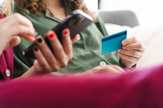 A person uses a smartphone and a credit card to make an online purchase.