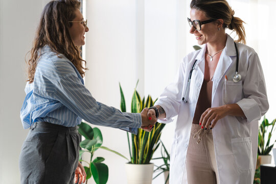 A doctor in a white coat shakes hands with a patient, signifying a positive consultation and the start of a healthcare journey.