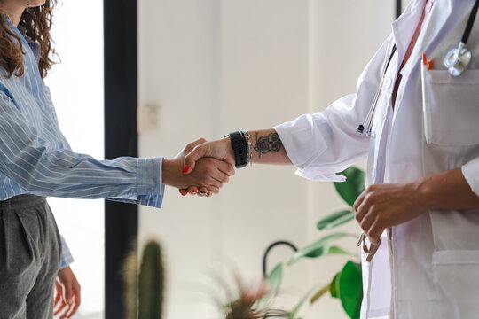 A patient and a medical professional shake hands, symbolizing trust and a successful consultation in a modern clinic setting.