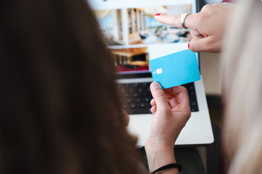 Two people are using a laptop and a debit card for online shopping or banking.