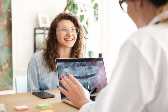 A dentist reviews a dental x-ray with a smiling patient, discussing treatment options in a modern clinic setting.