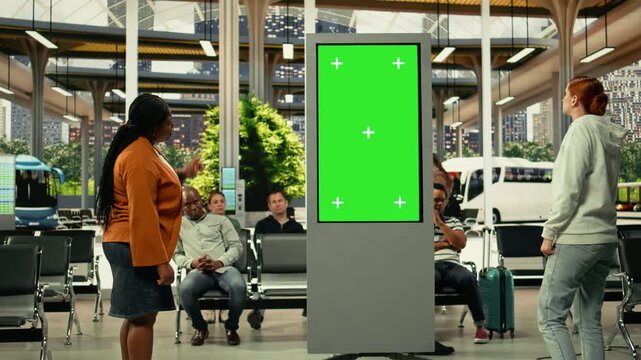 Green screen TV near dynamic city transportation scene with diverse people on the move in crowded bus terminal. Commuters of different ages create realistic everyday travel routine.