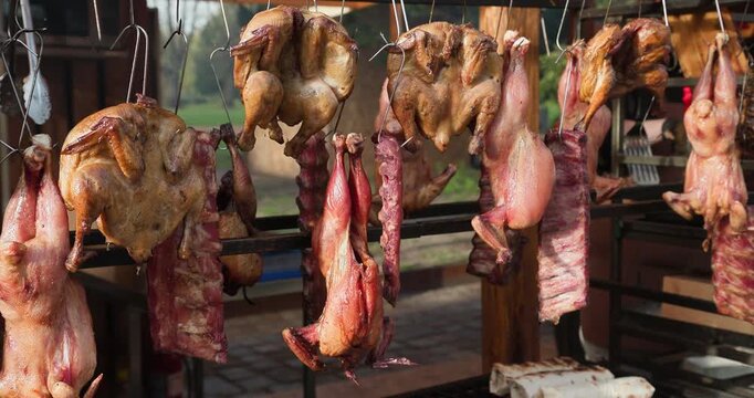 Panoramic overview of a street food stall displaying hanging roasted chickens, pork ribs, and fresh pineapples, with no people in the frame
