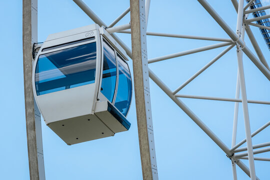 White cable car gondola suspended from a steel framework against a clear blue sky, showcasing modern design and engineering in an amusement park setting