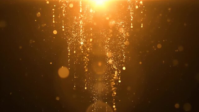 Shimmering golden particles falling from a bright light source on a dark background.
