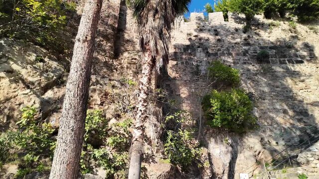 Ancient stone fortress wall with battlements in Kaleici old town Antalya under clear blue sky.