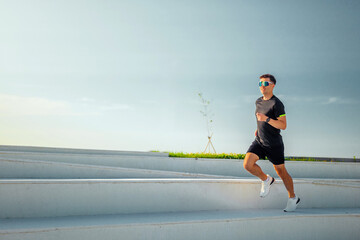 Fototapeta premium Young man runs energetically on outdoor steps during a sunny morning in a tranquil urban park